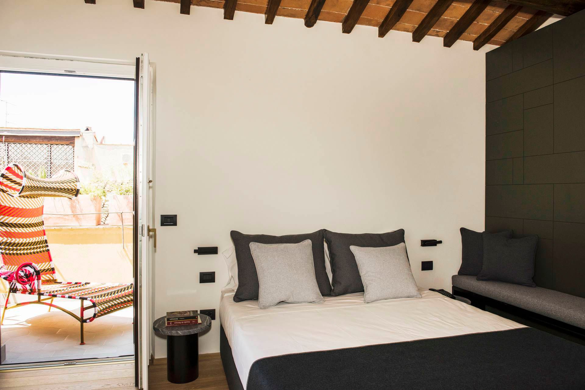Double bed with gray sheets in the deluxe room with terrace
